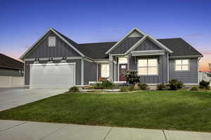 View of front facade featuring board and batten siding, concrete driveway, a yard, and a shingled roof