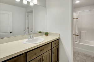 Bathroom featuring vanity, shower / bath combination with curtain, and light tile patterned flooring