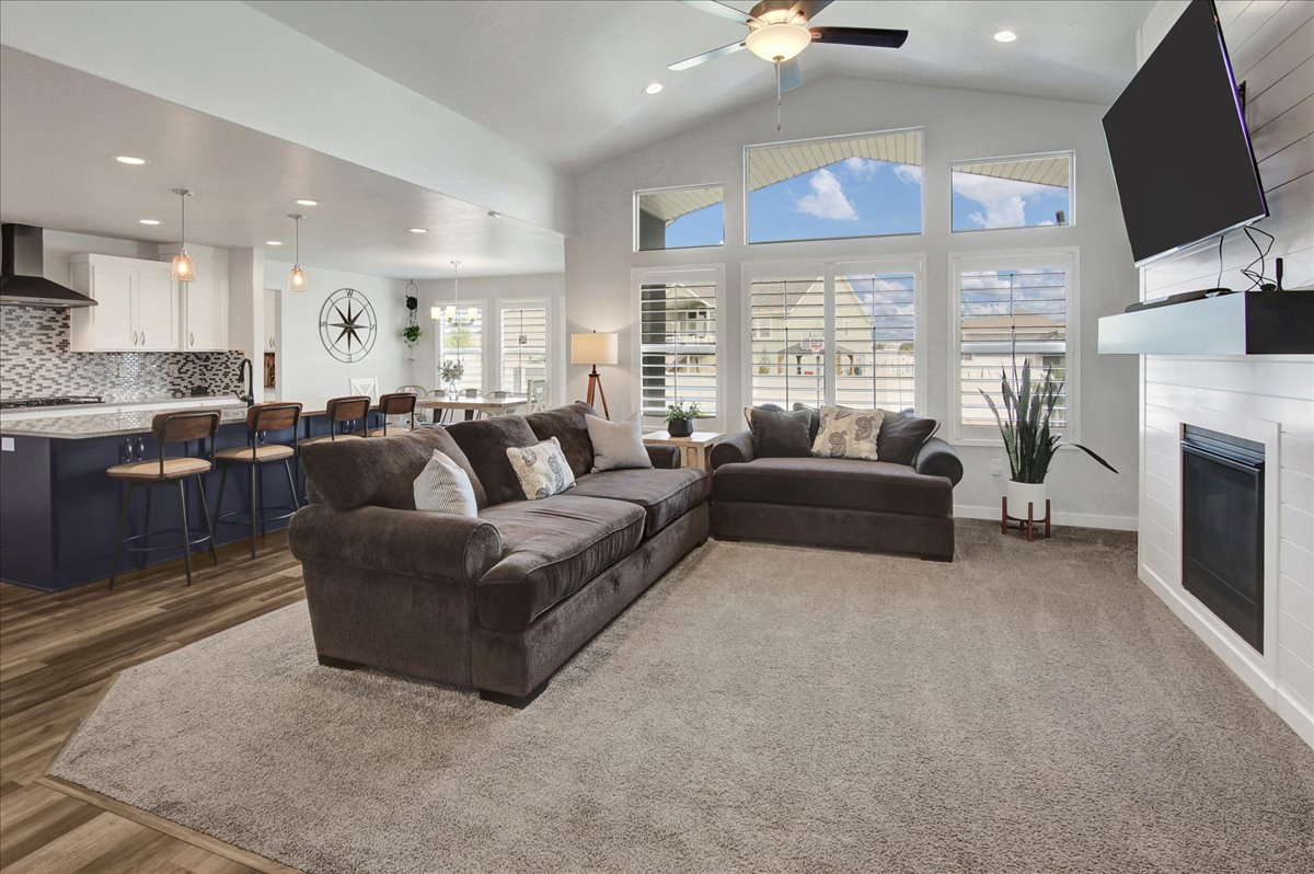 Living room featuring a glass covered fireplace, recessed lighting, high vaulted ceiling, and ceiling fan