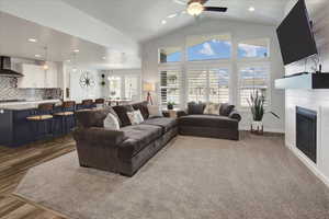 Living room featuring a glass covered fireplace, recessed lighting, high vaulted ceiling, and ceiling fan