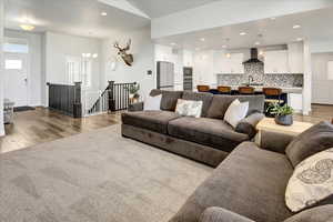 Living room featuring recessed lighting, light wood-style floors, a chandelier, and light colored carpet