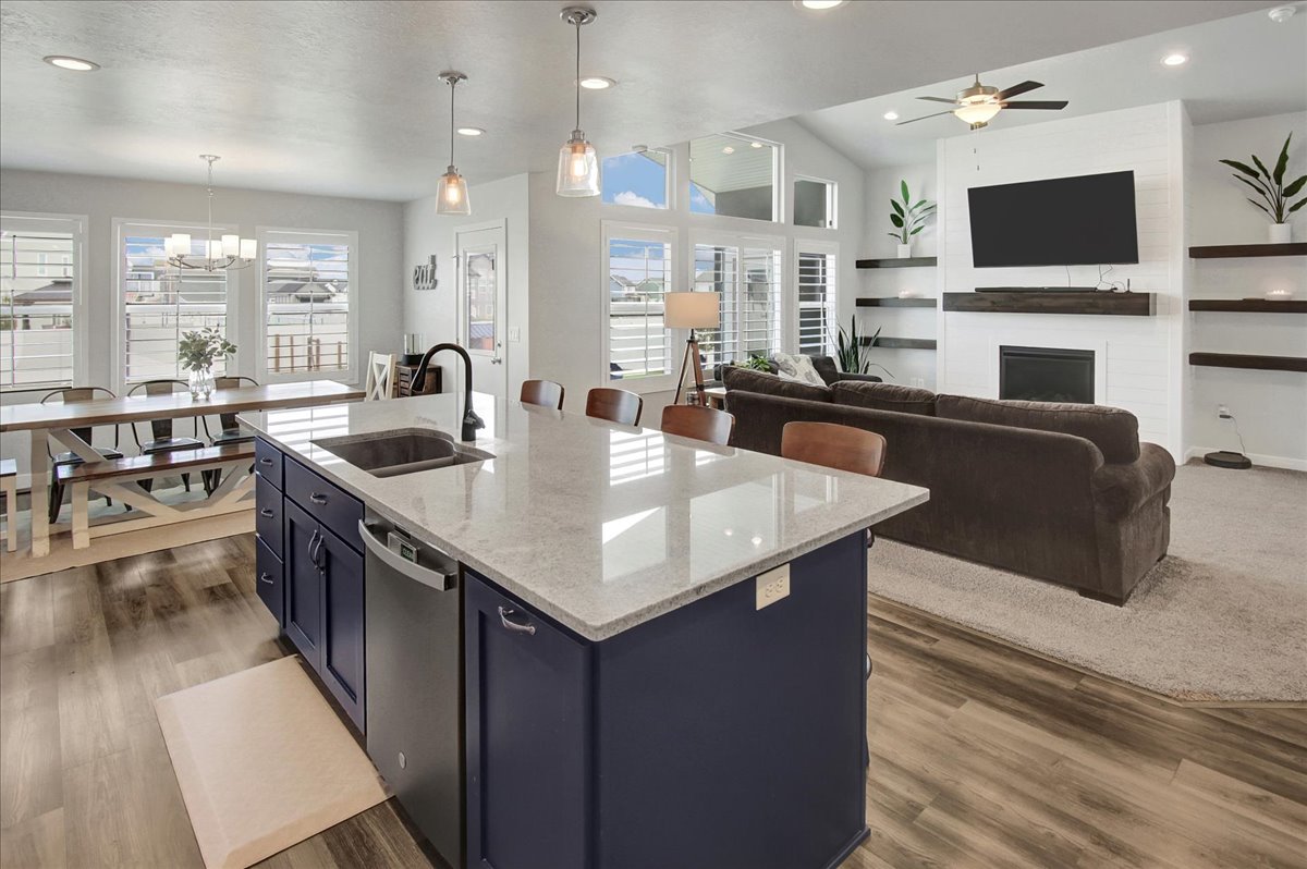 Kitchen featuring light stone countertops, recessed lighting, blue cabinets, hanging light fixtures, and stainless steel dishwasher