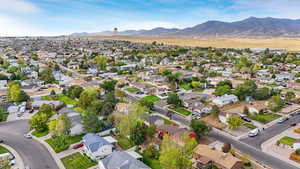Aerial view of property and surrounding area featuring nearby suburban area and a mountain backdrop