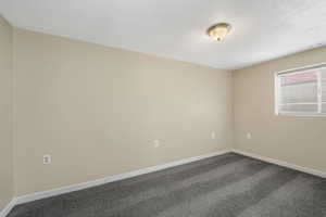 Empty room featuring dark colored carpet