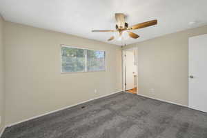 Unfurnished bedroom featuring carpet floors, ceiling fan, and ensuite bath