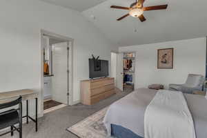 Carpeted bedroom with ensuite bathroom, vaulted ceiling, ceiling fan, and a spacious closet