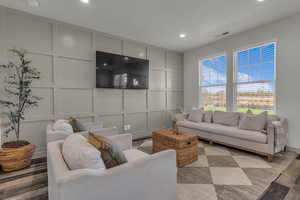 Living area with a decorative wall, wood finished floors, and recessed lighting