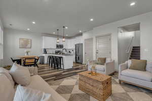 Living area with recessed lighting, dark wood-style flooring, and stairway