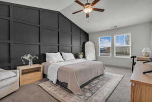 Bedroom featuring carpet floors, lofted ceiling, a decorative wall, and ceiling fan