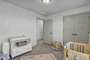 Carpeted bedroom featuring a closet and a crib