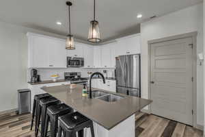 Kitchen featuring appliances with stainless steel finishes, decorative backsplash, white cabinets, light wood-type flooring, and recessed lighting