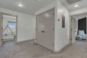 Corridor with light colored carpet, electric panel, and recessed lighting