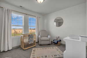 Carpeted bedroom featuring a nursery area and baseboards