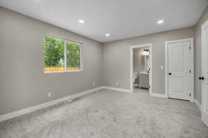 Unfurnished bedroom featuring light colored carpet, recessed lighting, and ensuite bath