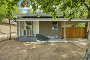 Rear view of house with roof with shingles, covered porch, and an attached carport