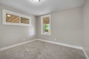 Carpeted empty room featuring baseboards and a textured ceiling