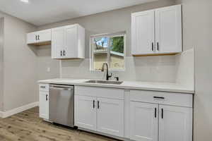 Kitchen with white cabinetry, tasteful backsplash, dishwasher, light wood-style flooring, and recessed lighting
