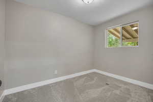 Carpeted spare room with baseboards and a textured ceiling