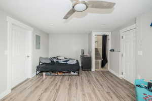 Bedroom with light wood-style flooring, a ceiling fan, electric panel, and recessed lighting