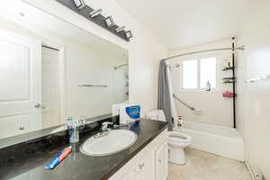 Bathroom with shower / tub combo, vanity, and light tile patterned floors