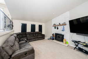 Carpeted living room with a wood stove and baseboards