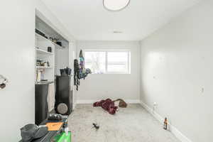 Exercise area with light carpet and baseboards