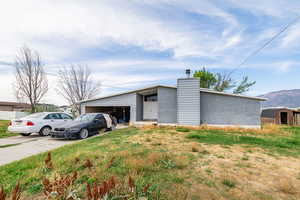 Mid-century inspired home with a chimney, driveway, an attached garage, a mountain view, and brick siding