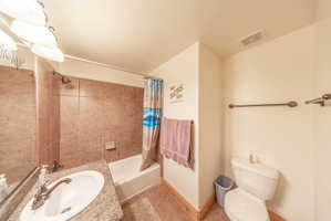 Full bath with vanity, light tile patterned floors, and shower / tub combo