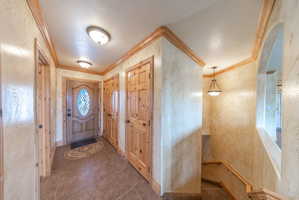 Foyer with ornamental molding and dark tile patterned flooring