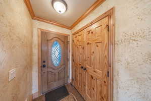 Foyer featuring ornamental molding and dark tile patterned floors