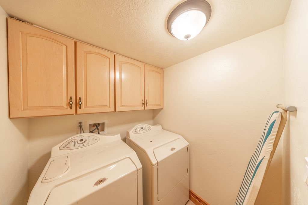 Laundry room featuring separate washer and dryer, cabinet space, and a textured ceiling
