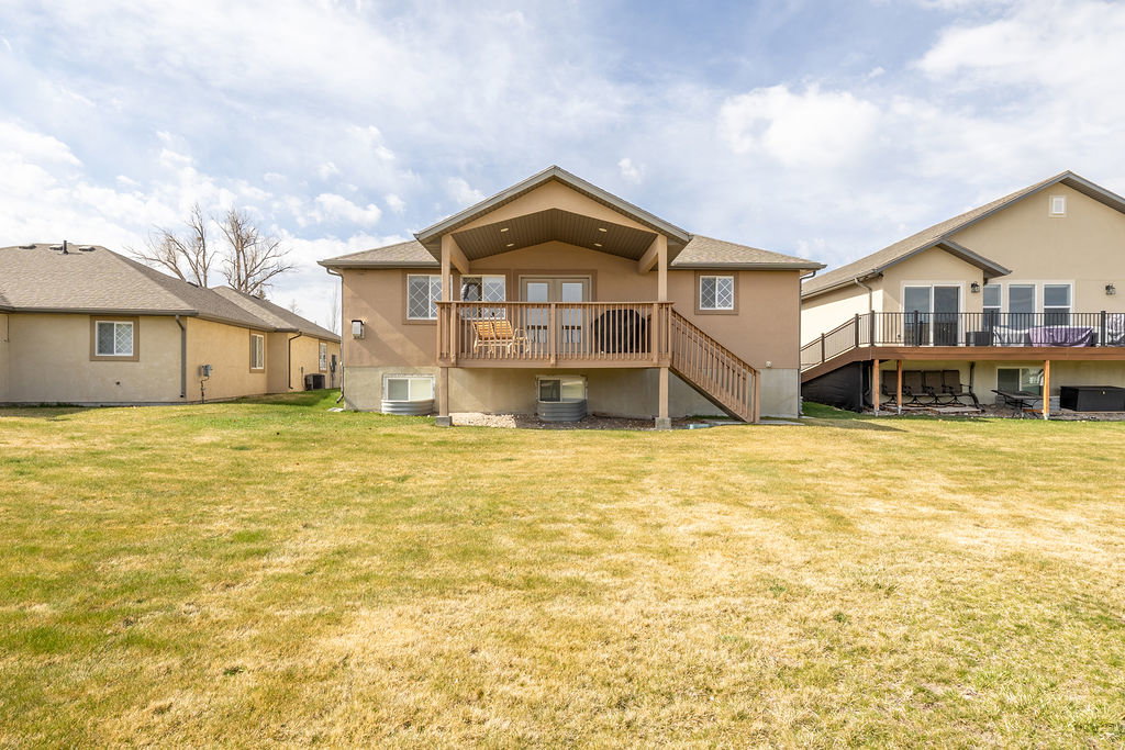 Rear view of property with a deck, a yard, stucco siding, and french doors
