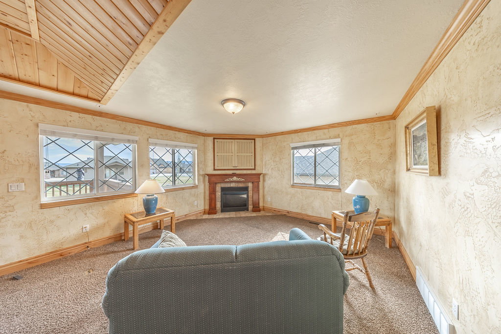 Carpeted living room with a fireplace, cooling unit, a textured wall, crown molding, and vaulted ceiling