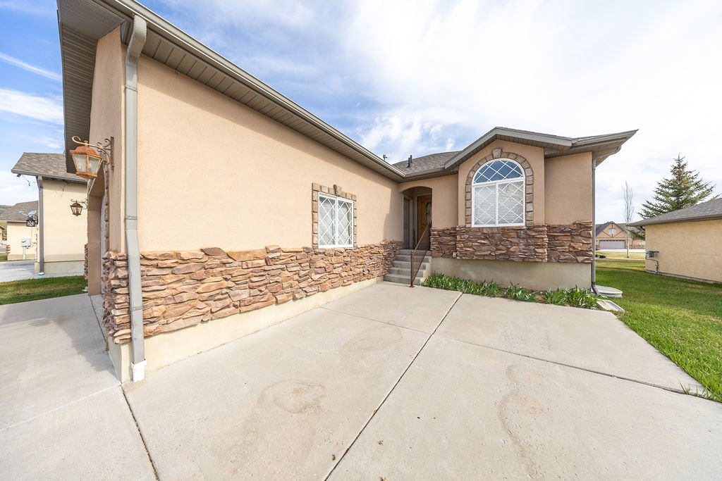 View of front of house with stucco siding, a patio area, and stone siding