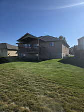 Rear view of house with a deck, a yard, and stairs