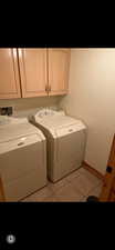 Laundry area featuring light tile patterned flooring, cabinet space, and washer and clothes dryer