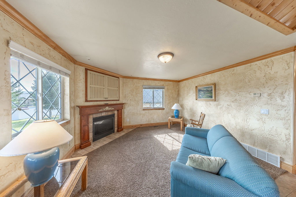 Living room featuring wallpapered walls, ornamental molding, a tiled fireplace, and carpet
