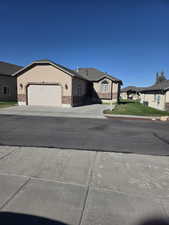 Ranch-style house featuring concrete driveway, an attached garage, stucco siding, and a front lawn