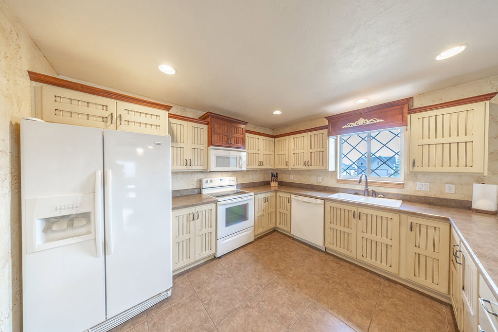 Kitchen featuring white appliances, cream cabinetry, glass fronted cabinets, light countertops, and light tile patterned floors