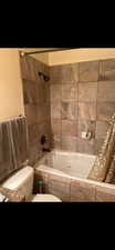 Bathroom with a combined bath / shower with jetted tub and toilet