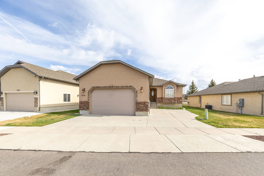 Single story home featuring stucco siding, a garage, driveway, and a front yard