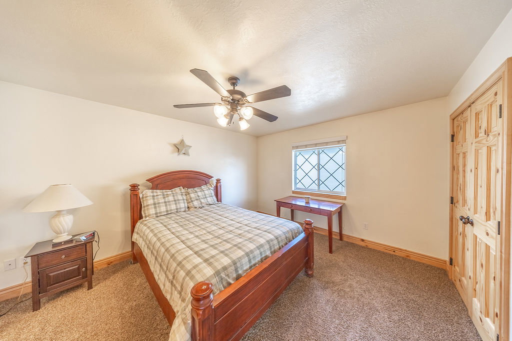 Carpeted bedroom with a closet, a ceiling fan, and a textured ceiling