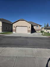 Ranch-style house featuring driveway, a garage, stucco siding, and brick siding