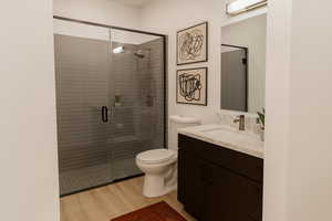 Full bathroom featuring vanity, a stall shower, and light wood-type flooring