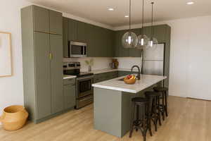 Kitchen featuring appliances with stainless steel finishes, a breakfast bar area, light countertops, light wood finished floors, and recessed lighting