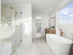 Full bath with a walk in closet, vanity, a stall shower, and a soaking tub