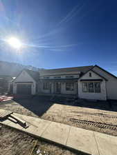 View of front of home with brick siding, an attached garage, driveway, a mountain view, and board and batten siding