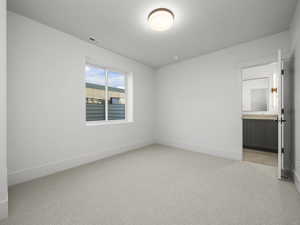 Unfurnished bedroom with light colored carpet and ensuite bath
