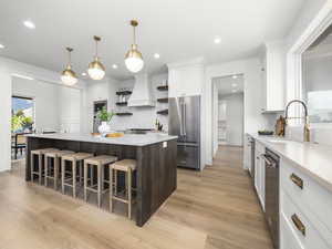 Kitchen with two tone color scheme, open shelves, stainless steel appliances, a kitchen bar, and light wood-style floors