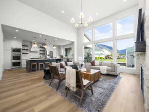 Living room with a mountain view, light wood-style flooring, a high ceiling, hanging lights, and a fireplace